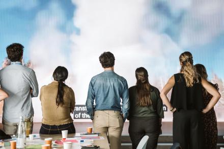 Group of people looking at a mural of a sky full of white clouds