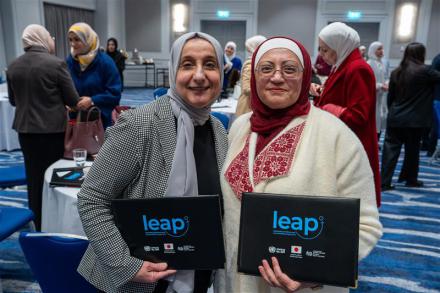 Two course participants holding L.E.A.P. branded document folders