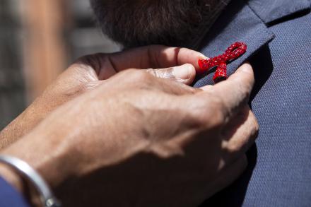close-up of person putting on HIV awareness red ribbon pin