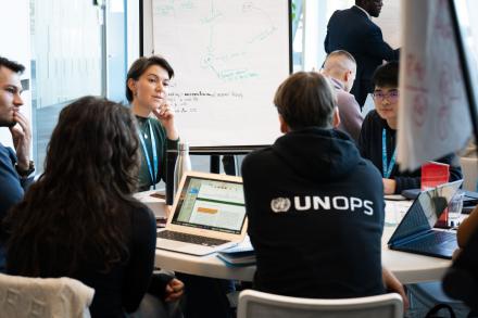 Programme participants discussing. One participant is wearing the UNOPS hoodie