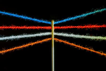 four colourful threads through a needle