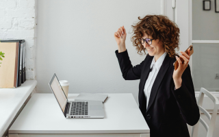A photo of a women at her work desk, happy with her achievements 