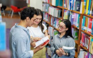 Three young people reading a book in a library