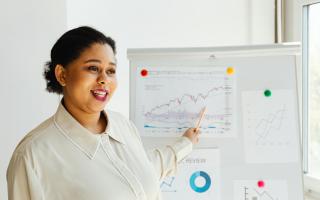 Woman in front of whiteboard presenting data