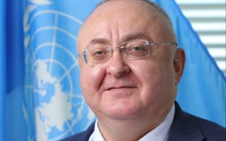 portrait of Zurab Elzarov in front of UN flag