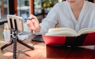 A woman looking at a phone and a book