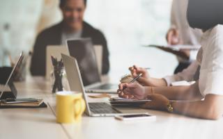 Two people sitting at a table in front of their laptops