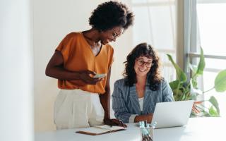 Two people looking at a laptop screen, smiling