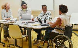 Colleagues, including a person in a wheelchair, around a table